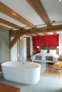 chambre double avec salle de bain ouverte sur la chambre et poutre apparente au plafond