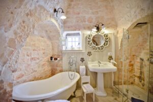 Salle de bain avec mur en pierres apparentes avec baignoire dans un trullo Leonardo Trulli Resort Pouilles
