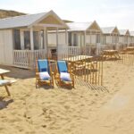 Vue extérieure des cabanons avec morceau de plage privative et table dans le sable