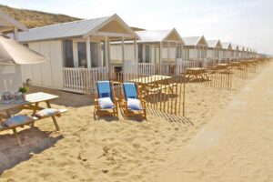 Vue extérieure des cabanons avec morceau de plage privative et table dans le sable