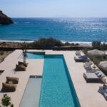 belle piscine et transat au bord de mer dans un hôtel avec des cours de yoga en Grèce