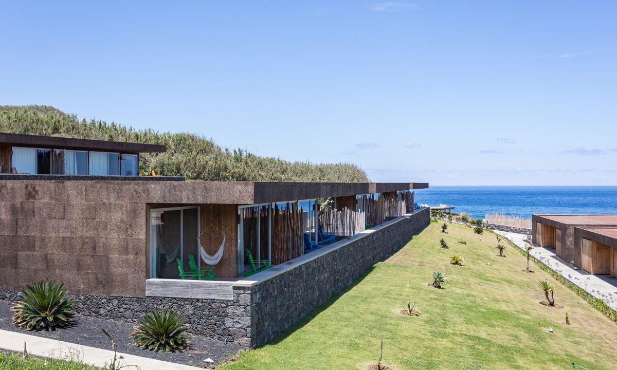 Vue extérieure des villas et de leur terrasse. Le bâtiment est construit pour se fondre dans le paysage de l'île avec son toit terrasse
