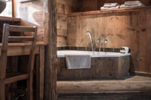 Salle de bain avec baignoire ouverte sur la chambre au Chalet 1864, chambre d'hôtes à la montagne