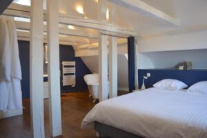 chambre avec beaucoup de cachet avec sa salle de bain ouverte et ses poutres apparentes