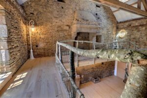 Rénovation intérieure d'une longère en respectant les matériaux naturels. La grande chemine a été gardée, les murs en pierre, les poutres en bois. Balustrade réalisée en branches d'arbres et touche originale avec le candélabre de rue en luminaire