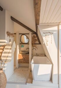 Salle de bain joliment décorée dans un esprit bohème chic avec baignoire ilot dans la soupente du toit