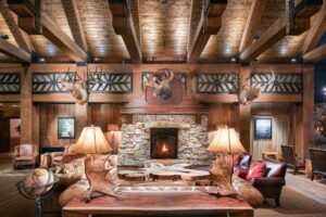 salon cosy et chaleureux avec grande cheminée en pierre entourée de canapés Chesterfield