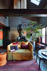 salon avec bibliothèque et décoration très artistique dans une suite à louer à Bruges