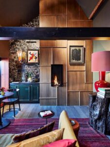 Salon d'une suite à Bruges avec sa cheminée au gaz et sa décoration éclectique et colorée