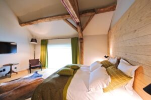 chambre double standard avec poutres apparentes et utilisation du bois sur les murs et au sol