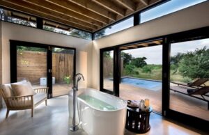 salle de bain avec baignoire ilot ouverte sur la terrasse avec la piscine privée et vue sur la brousse