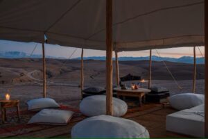 salon illuminé à la bougie sous une tente dans le désert au coucher du soleil au Maroc