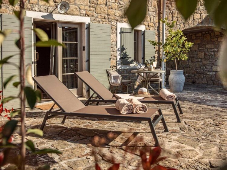 terrasse d'une chambre avec transat , tables et chaises