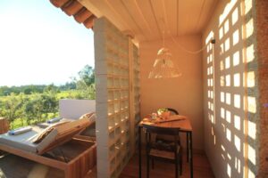 terrasse de la suite de l'hôtel Vinha by Nhôme avec transat donnant sur les vignes et coin repas