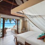 vue intérieure du bungalow avec le lit faisant face à la plage et à la mer paradisiaque