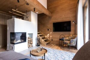salon d'un des chalets avec cheminée et ouvrant sur une terrasse avec vue panoramique