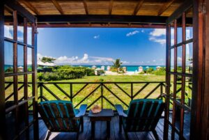 vue sur le jardin, la plage et la mer depuis la terrasse ombragée d'une des chambres de l'hôtel