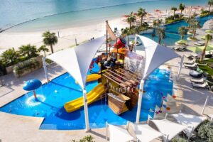 piscine dédiée aux enfants avec des modules de jeux et jouxtant la piscine avec toboggan