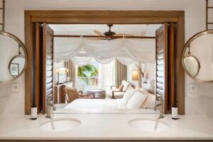 salle de bain ouverte sur la chambre via une fenêtre avec des persiennes