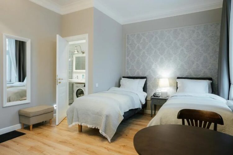 chambre avec lits jumeaux et lave linge dans la salle de bain dans une résidence d'appartements à louer de Riga