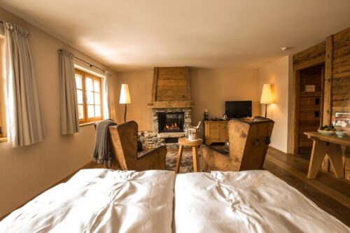 chambre cosy et chic avec une belle cheminée dans l'hôtel de charme Maiensässhotel Guarda Val