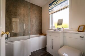 salle de bain du cottage comprenant baignoire avec douche, lavabo et wc