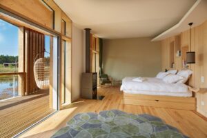 lodge suspendu au-dessus de l'eau avec poêle à bois dans la chambre et terrasse à la vue panoramique sur le lac
