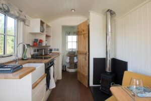 intérieur du lodge avec salle de douche, poêle à bois et kitchenette équipée