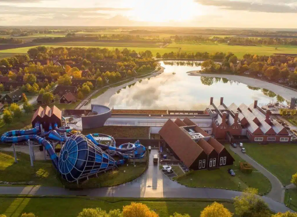 Vue en hauteur avec la piscine à toboggan, le lac, les plages et les maisons du village vacances Hof Van Saksen