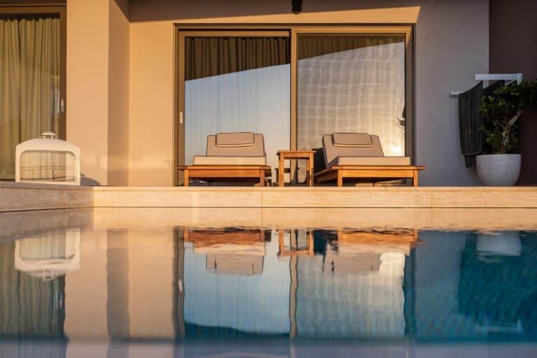 Reflet des transats dans l'eau calme de la piscine privée