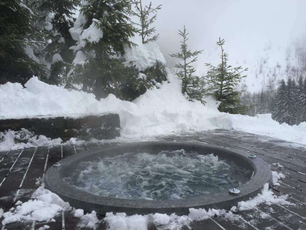 jacuzzi extérieur en plein hiver sous la neige en pleine montagne dans les Alpes
