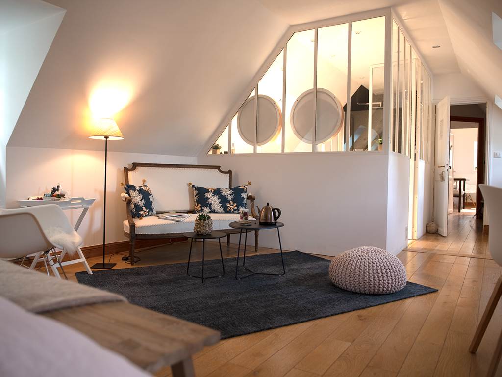 petit salon cosy et chaleureux avec la salle de bain derrière la verrière dans la chambre Glénan