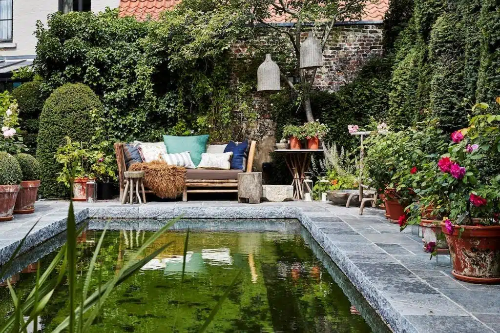 Piscine extérieure naturelle et tout en pierre se fondant parfaitement dans le jardin et dans un univers apaisant à la Maison Fred Luxury Suites à Bruges