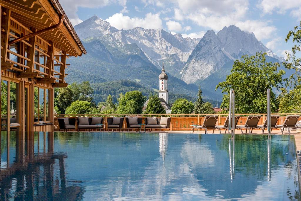 Carte postale de la Bavière avec son chalet en bois, la piscine extérieure chauffée et les montagnes à l'arrière plan