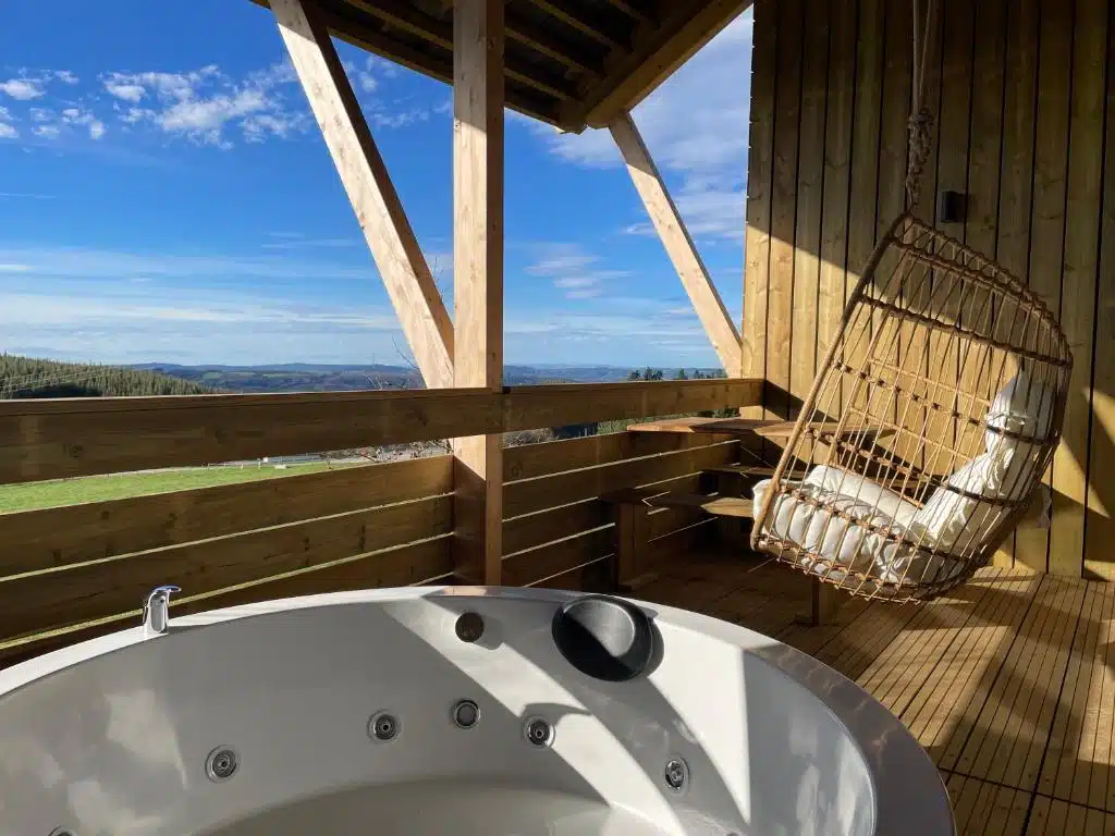 jacuzzi et fauteuil suspendu sur la terrasse du chalet